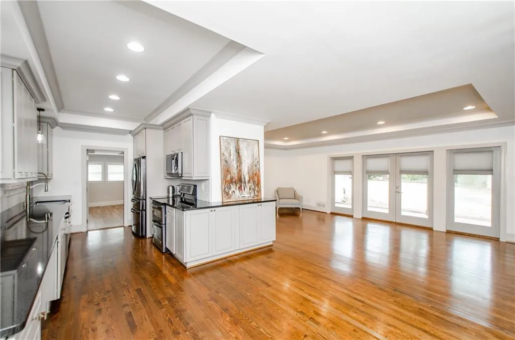 Kitchen with a raised ceiling, stainless steel appliances, open floor plan, dark wood-type flooring, and recessed lighting