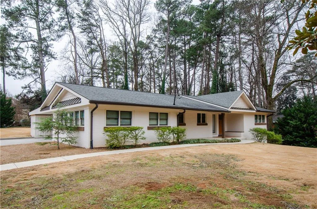 Ranch-style house featuring covered porch, roof with shingles, and brick siding