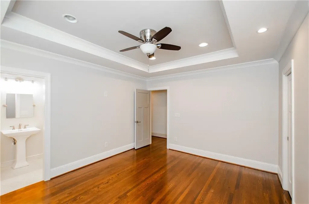 Unfurnished bedroom with a raised ceiling, hardwood / wood-style flooring, a ceiling fan, ornamental molding, and recessed lighting