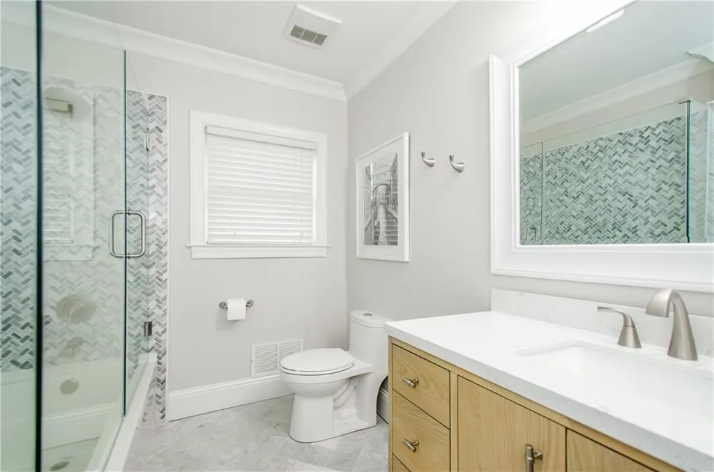 Bathroom featuring vanity, crown molding, combined bath / shower with glass door, and light marble finish floors