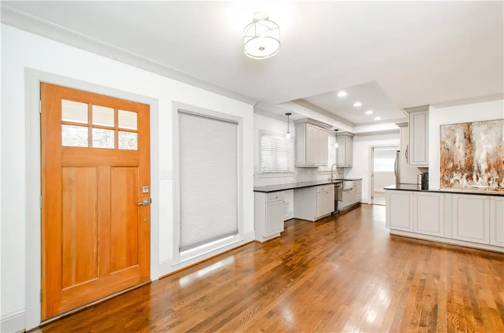 Foyer entrance with crown molding, light wood-style floors, a tray ceiling, and recessed lighting