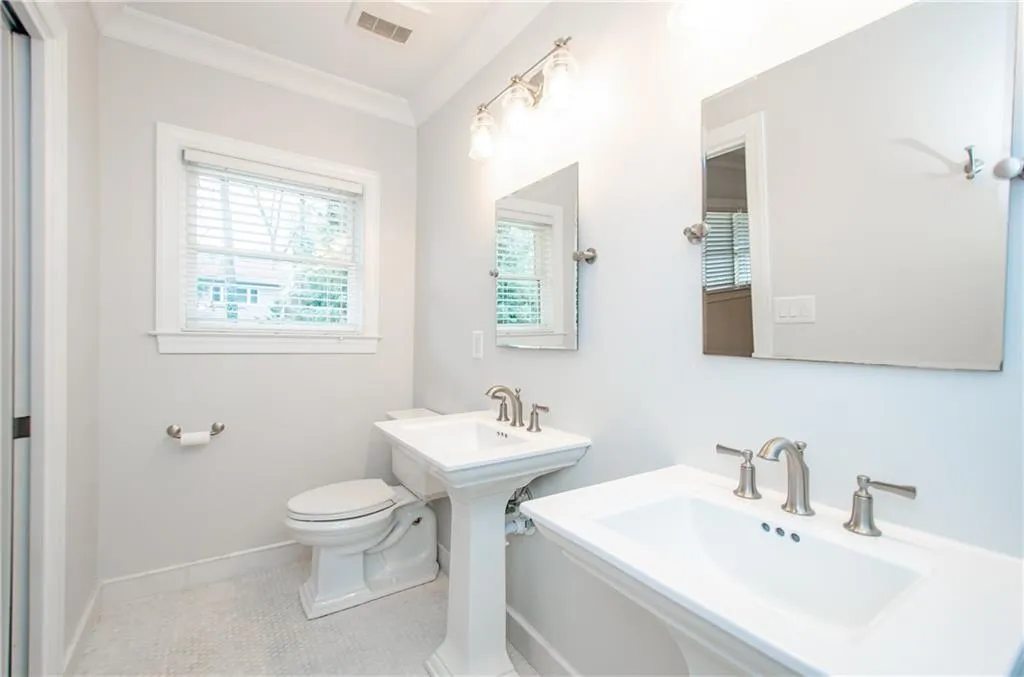 Bathroom featuring light tile patterned floors, two sinks, and crown molding
