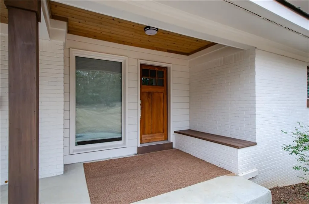 View of exterior entry featuring brick siding and a patio