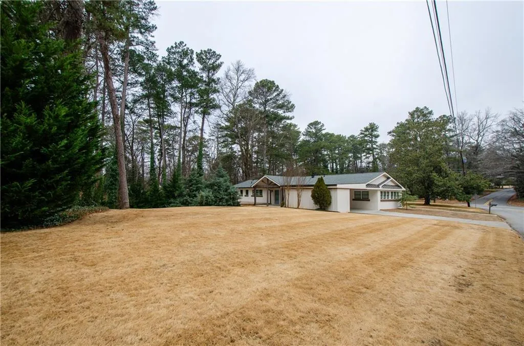 Ranch-style house featuring a front lawn and view of scattered trees