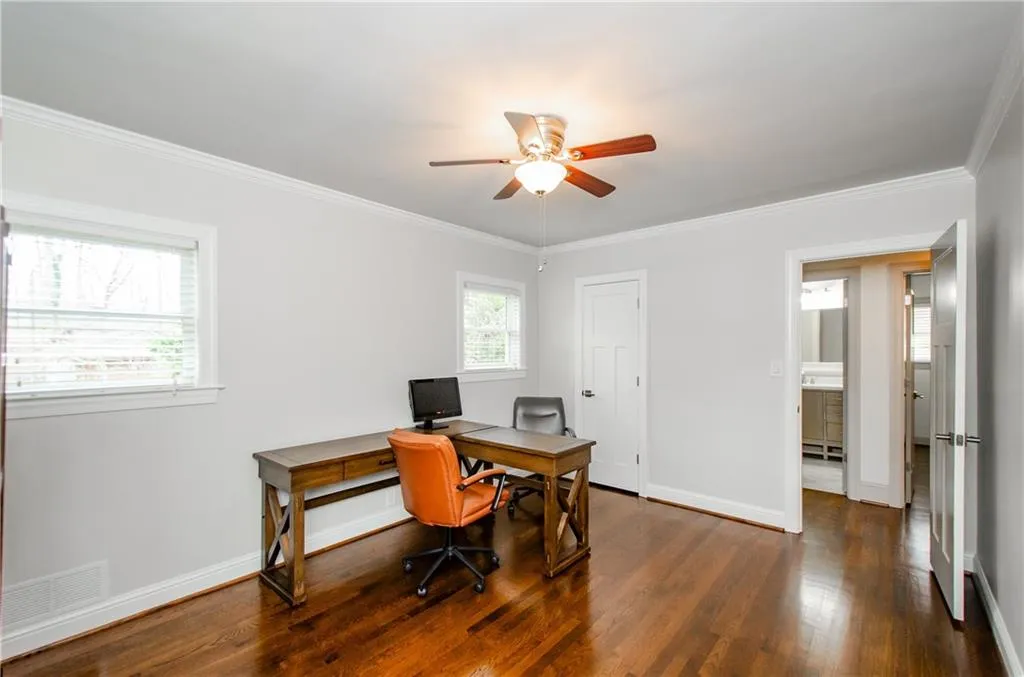 Office area featuring dark wood finished floors, ceiling fan, and ornamental molding