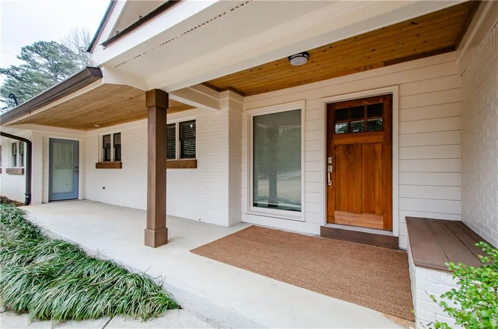 View of exterior entry with brick siding and a patio area