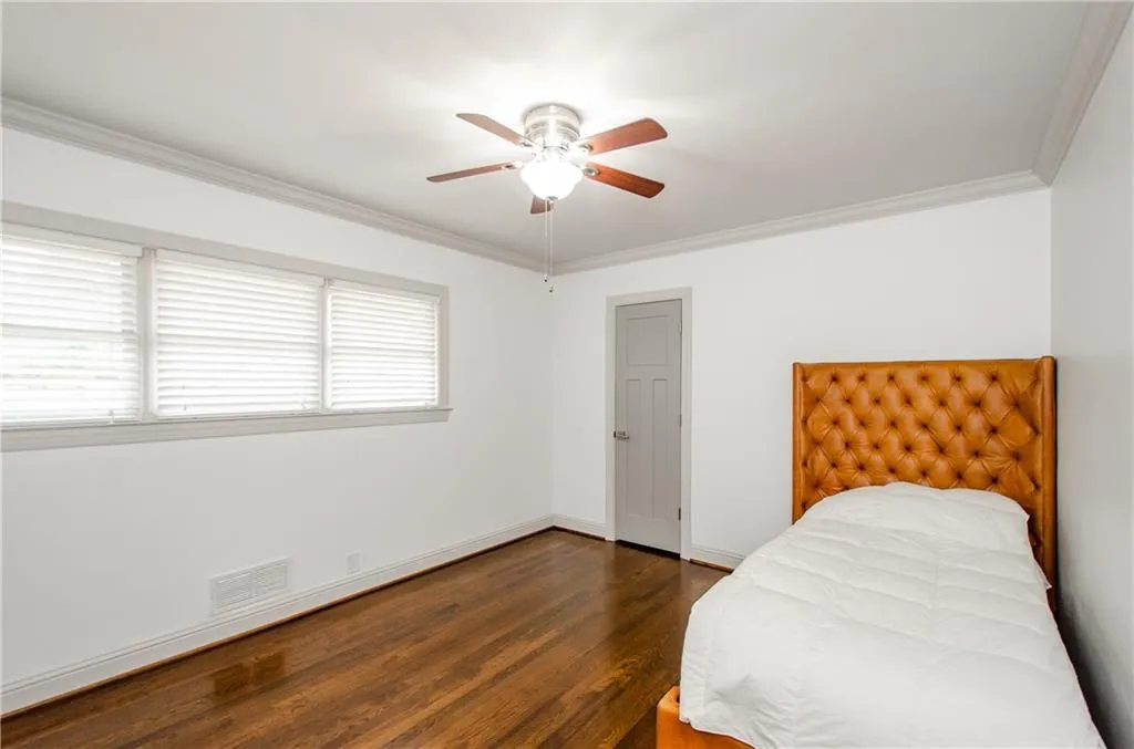 Bedroom with dark wood-type flooring, crown molding, and ceiling fan