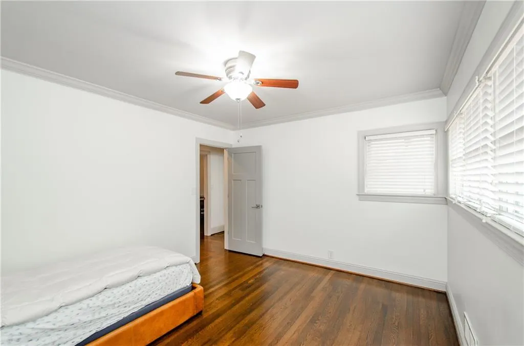 Unfurnished bedroom featuring crown molding, hardwood / wood-style flooring, and ceiling fan