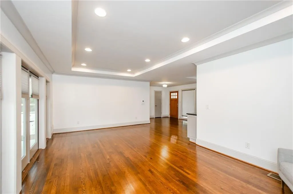 Spare room with light wood-style floors, crown molding, recessed lighting, and a raised ceiling