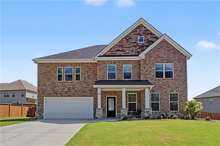 Brick and stone facade residence featuring a covered front porch, two-car garage, and gabled rooflines