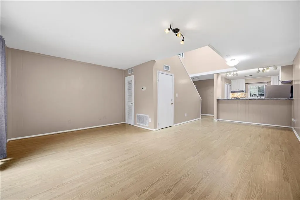 Unfurnished living room with rail lighting and light wood finished floors