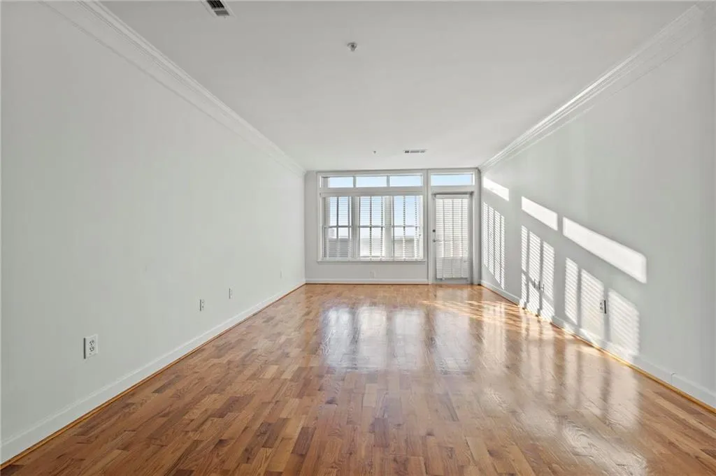 Unfurnished living room featuring ornamental molding and wood finished floors