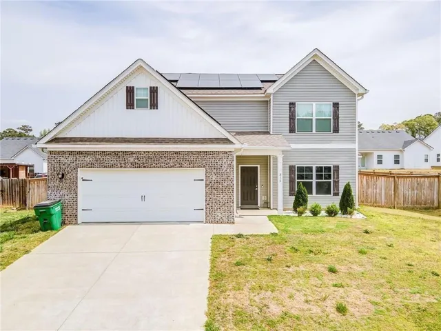 Traditional-style house with brick siding, concrete driveway, solar panels, and a shingled roof