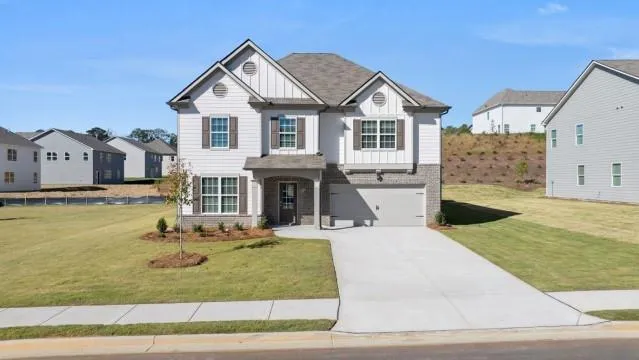 Two-story residence featuring light siding, brick accents, a gabled roof, an attached garage, and a concrete driveway
