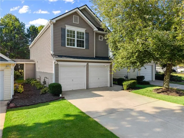 Two-car garage with white garage doors, asphalt shingle roof, and light-colored siding