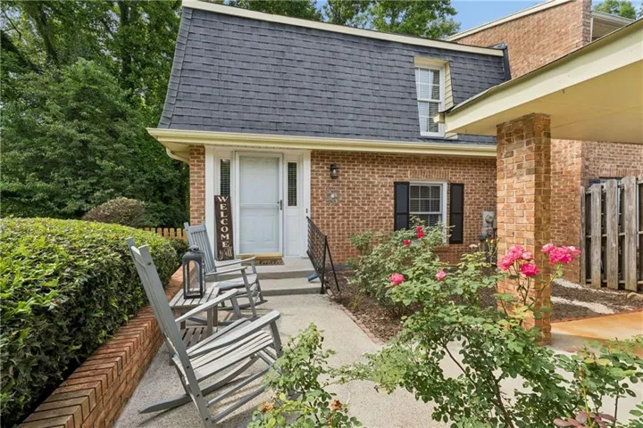 Brick exterior featuring a Mansard roofline, a white entry door with a storm door, and a dormer window