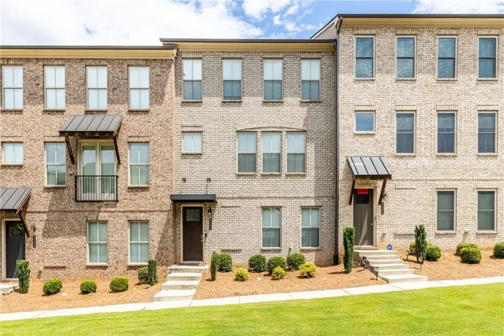 Brick exterior with multiple windows, individual entryways, and manicured landscaping