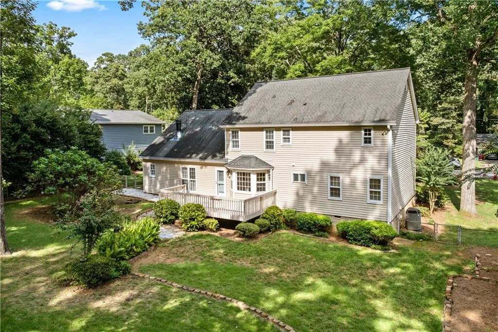 Drone photo shows rear of home, large wood deck and playable yard.