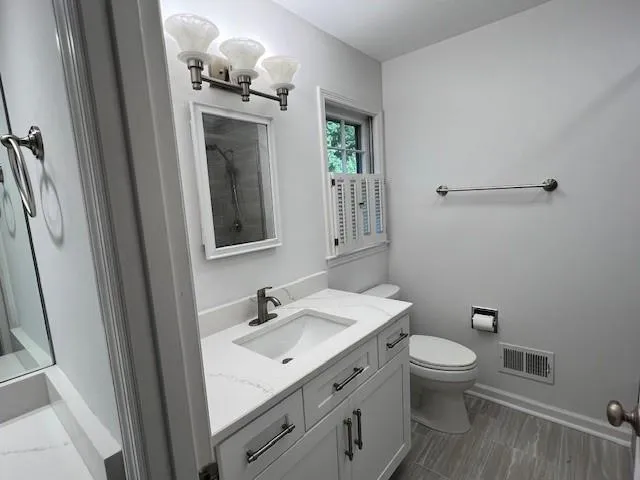Primary bathroom featuring a new vanity, new tiled shower and new tile floor.