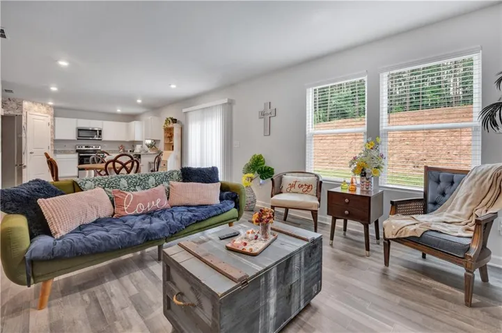 Open-concept living area featuring wood-finish flooring, recessed lighting, and ample natural light from multiple windows