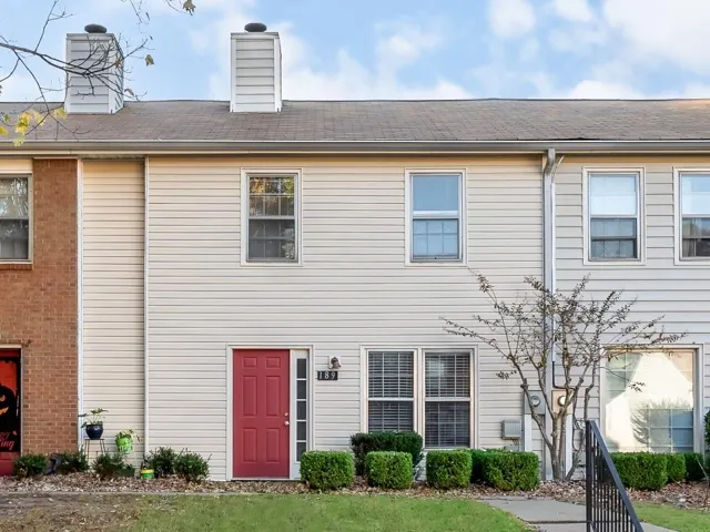 Two-story siding exterior with a red paneled entry door and transom window