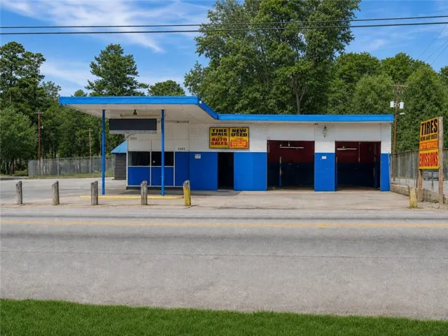 Commercial building with multiple service bays, an attached covered area, and a paved front lot
