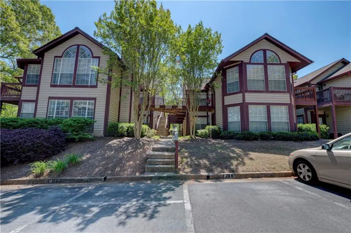 View of front facade featuring a wooden deck and uncovered parking