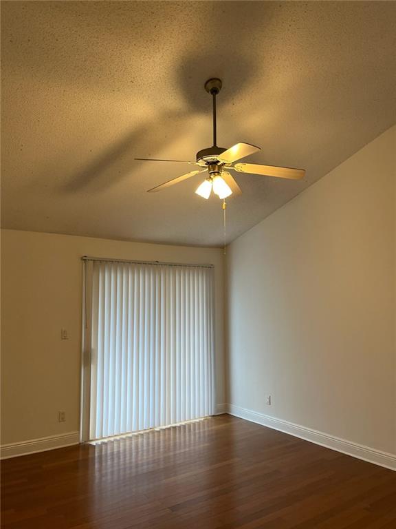 Unfurnished room featuring dark hardwood / wood-style flooring, ceiling fan, and a textured ceiling