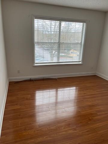Spare room with a textured ceiling and wood-type flooring