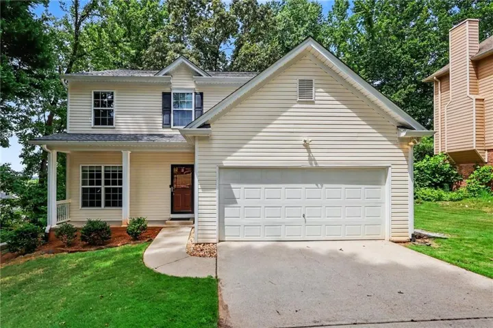 Two-story home with light-colored siding and a covered front porch featuring white columns