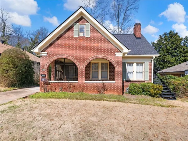 Brick exterior with a gabled roofline, arched porch entryways, and a brick chimney