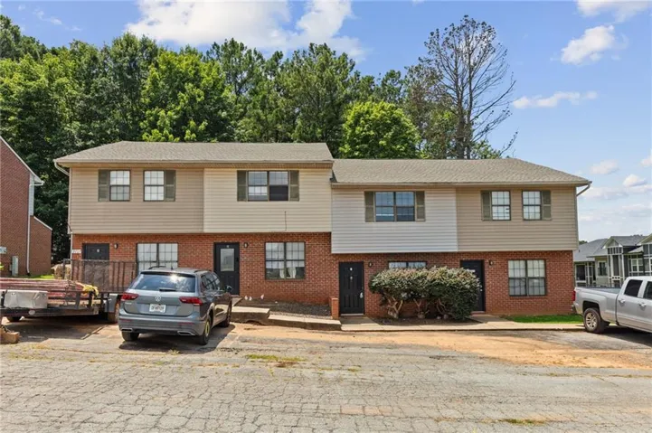 Duplex property featuring a brick and siding exterior with multiple windows