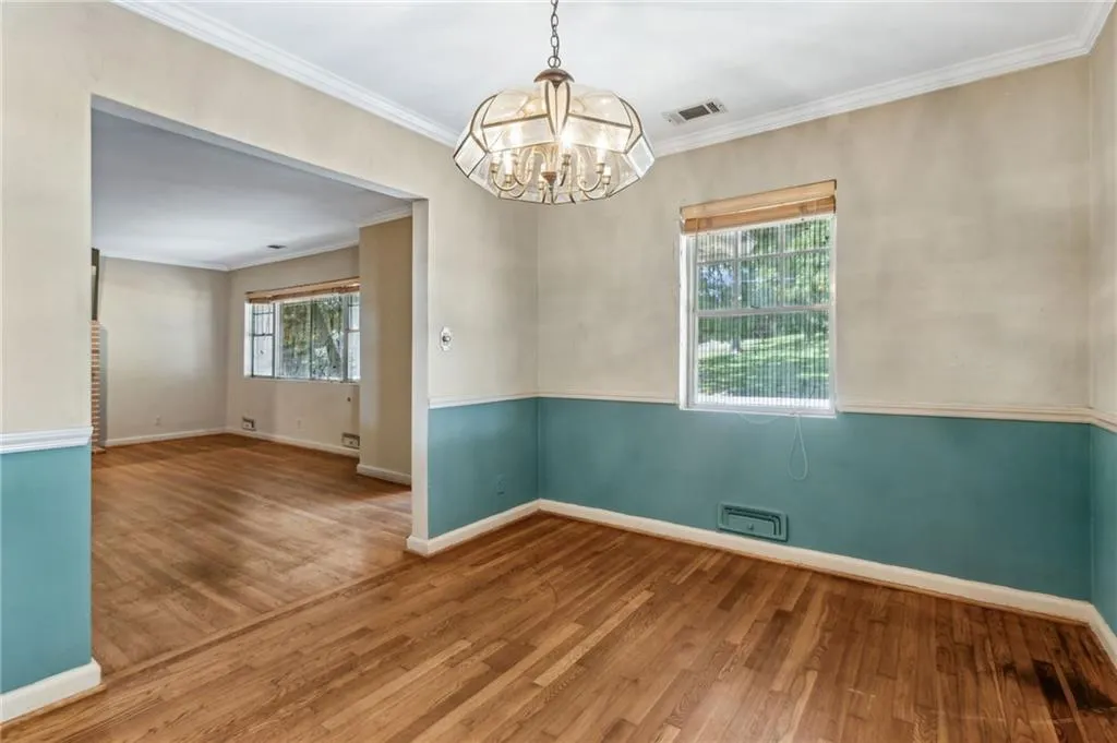 Separate Dining Room with crown molding, wood finished floors, and a chandelier
