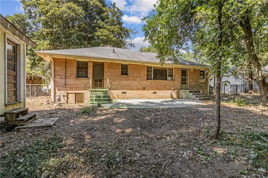 Back of property featuring crawl space, entry steps, a shingled roof, and brick siding