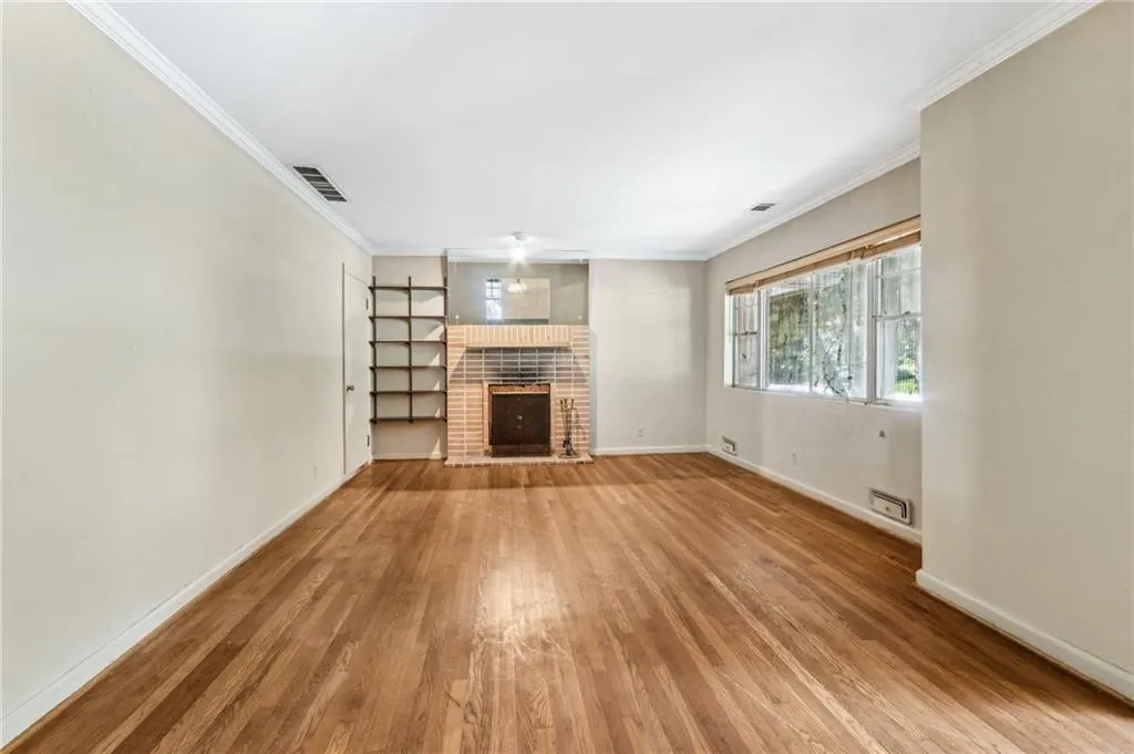 Living room featuring ornamental molding, a brick fireplace, and light wood-type flooring