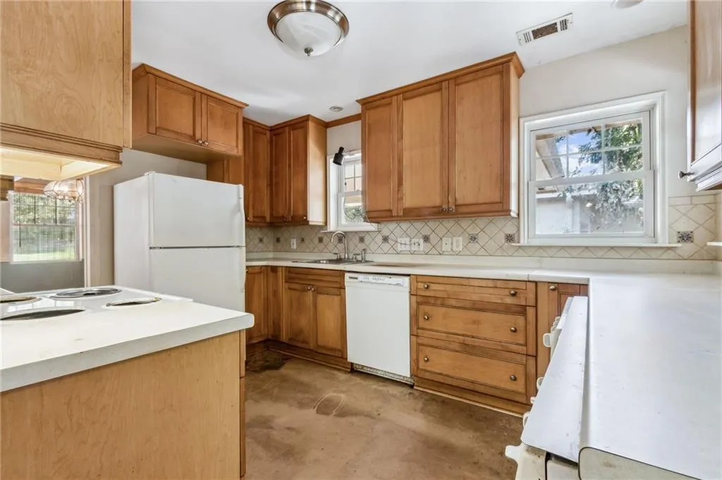 Kitchen with light brown cabinetry, white appliances, decorative backsplash, and light countertops