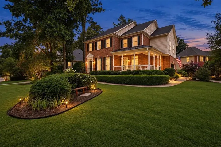 Brick exterior with a covered front porch featuring white columns and railings - Virtual Twilight