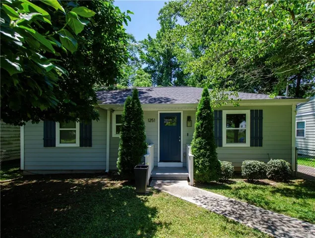 Light gray siding exterior with dark blue shutters, a dark blue entry door, and a concrete walkway