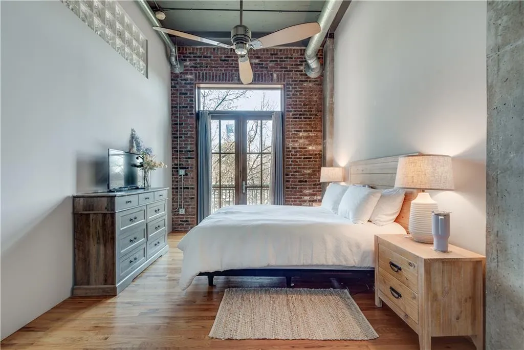 Bedroom with wood finished floors and brick wall