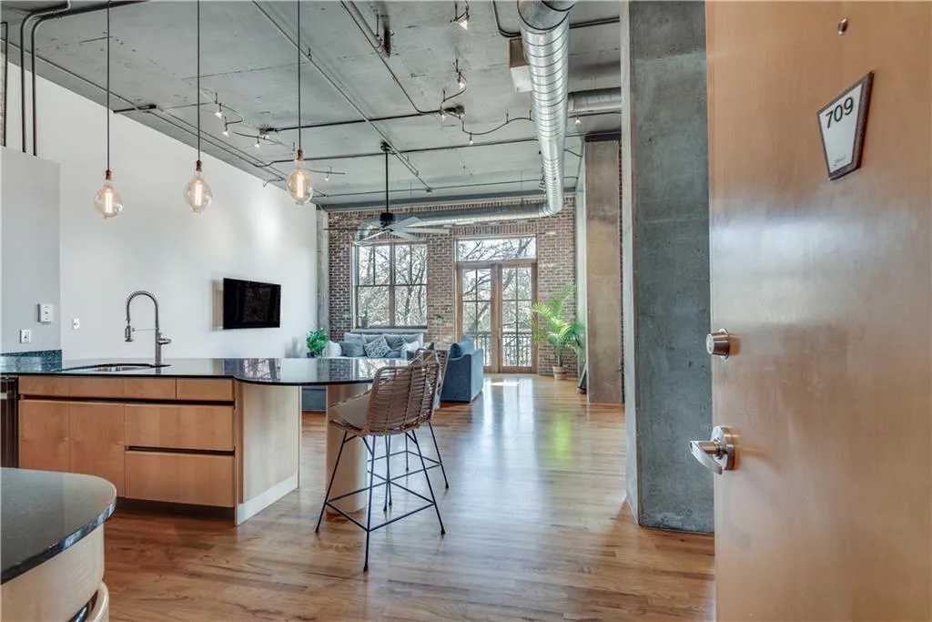 Kitchen with wood finished floors, a towering ceiling, open floor plan, ceiling fan, and a breakfast bar