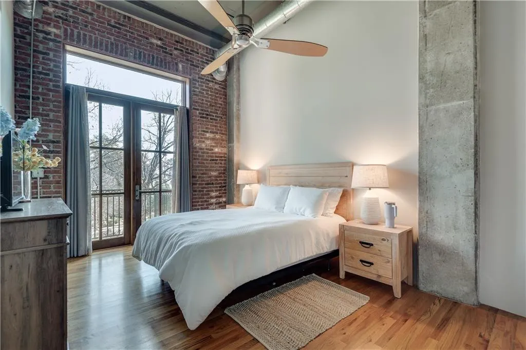 Bedroom with brick wall, wood finished floors, access to outside, and a ceiling fan