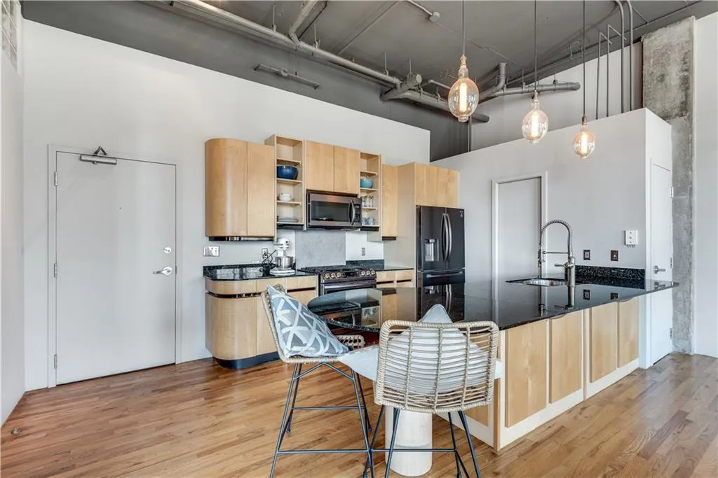 Kitchen featuring a towering ceiling, open shelves, light brown cabinets, a peninsula, and stainless steel appliances