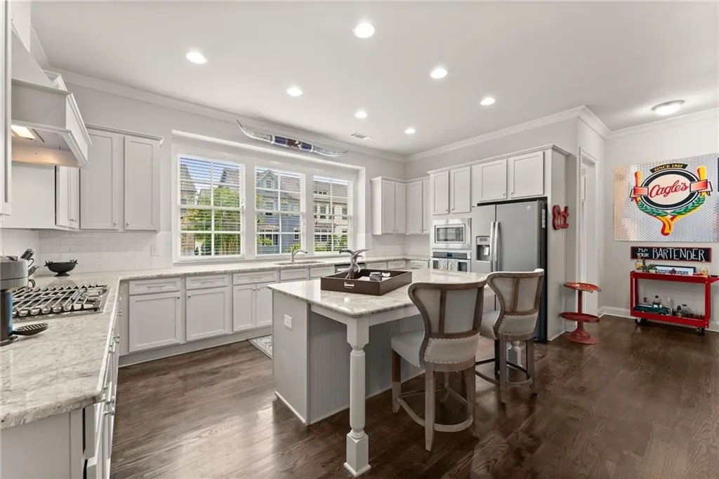 Kitchen featuring decorative backsplash, crown molding, white cabinetry, a center island, and a breakfast bar area