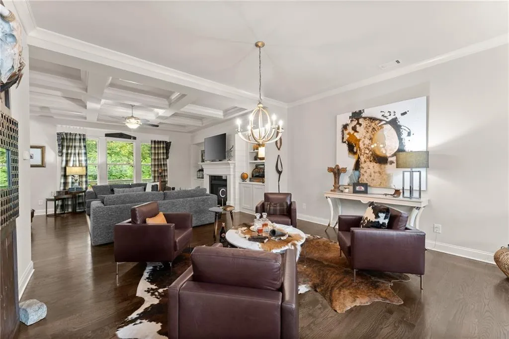 Living room featuring a fireplace, beamed ceiling, coffered ceiling, dark wood-type flooring, and ornamental molding