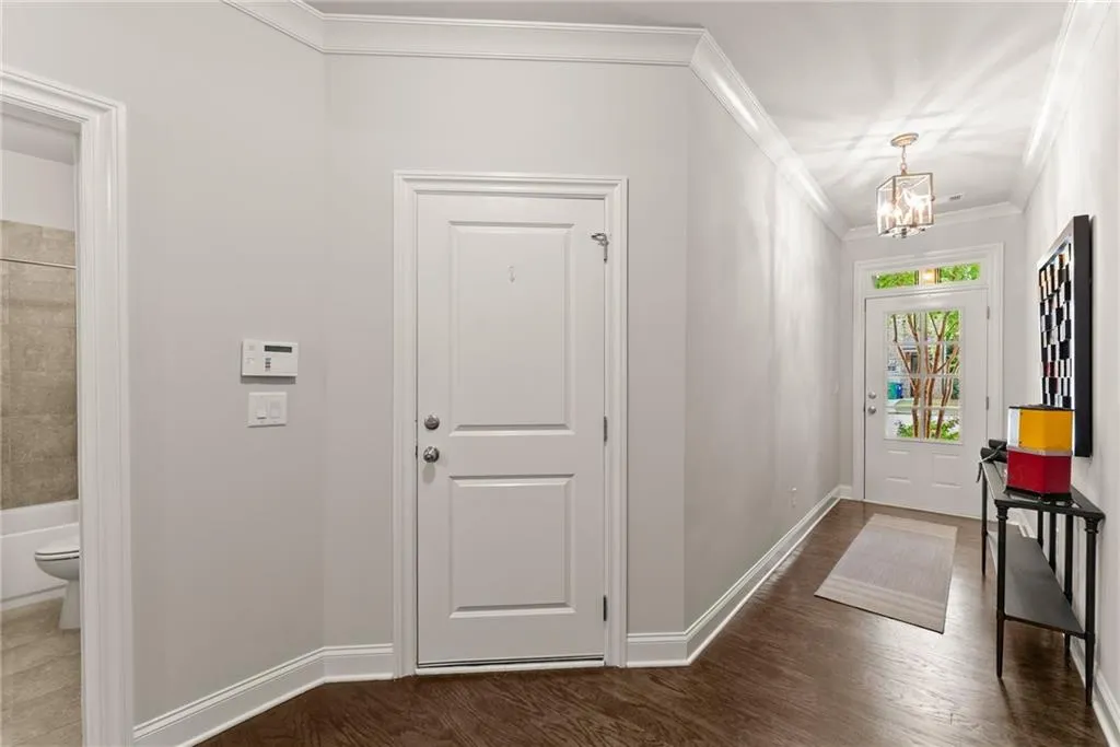 Entryway featuring crown molding, a chandelier, and dark wood-type flooring