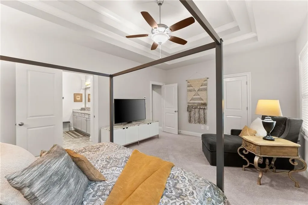 Bedroom featuring a tray ceiling, carpet floors, and a ceiling fan