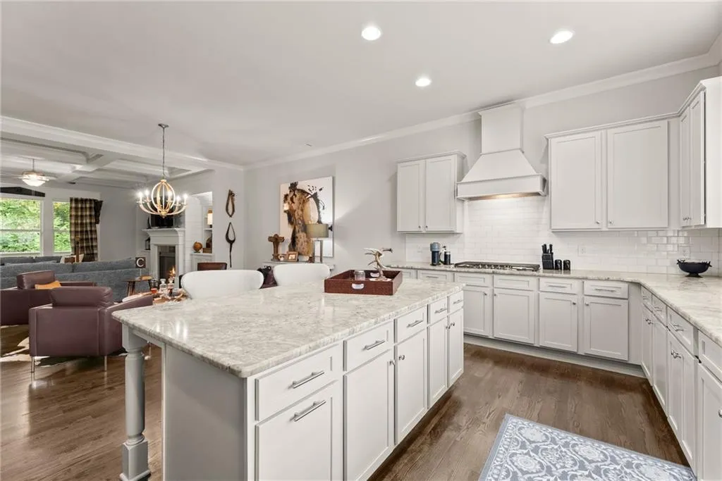 Kitchen with a breakfast bar area, white cabinetry, crown molding, light stone countertops, and recessed lighting