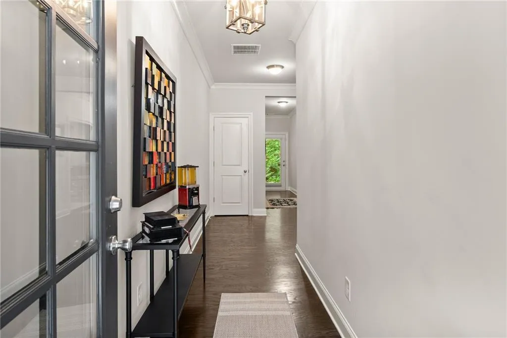 Hallway with crown molding, dark wood-style flooring, and a chandelier