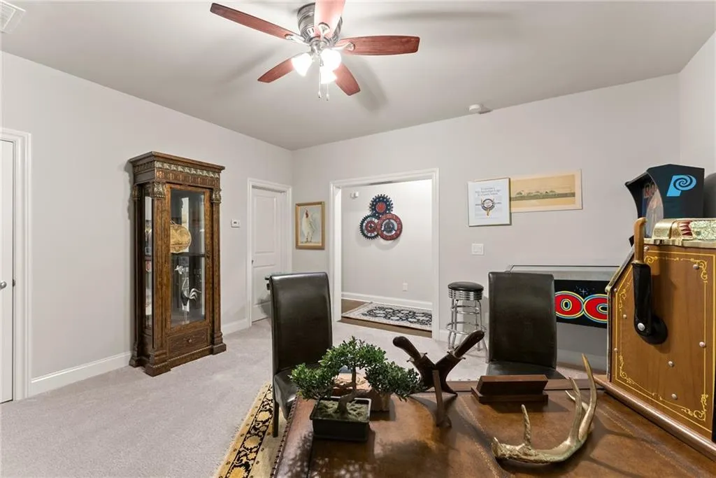 Carpeted office featuring a ceiling fan and baseboards