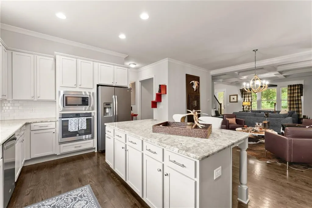 Kitchen with white cabinetry, coffered ceiling, beam ceiling, appliances with stainless steel finishes, and decorative backsplash